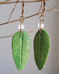 This image features a pair of handcrafted Crystal Guava Leaf Earrings, designed to capture the essence of nature-inspired artistry. The earrings are made using the papier-mâché technique, resulting in a unique, non-molded design for each piece.