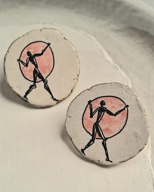 Round earrings with a design of a figure in a circle on a light background