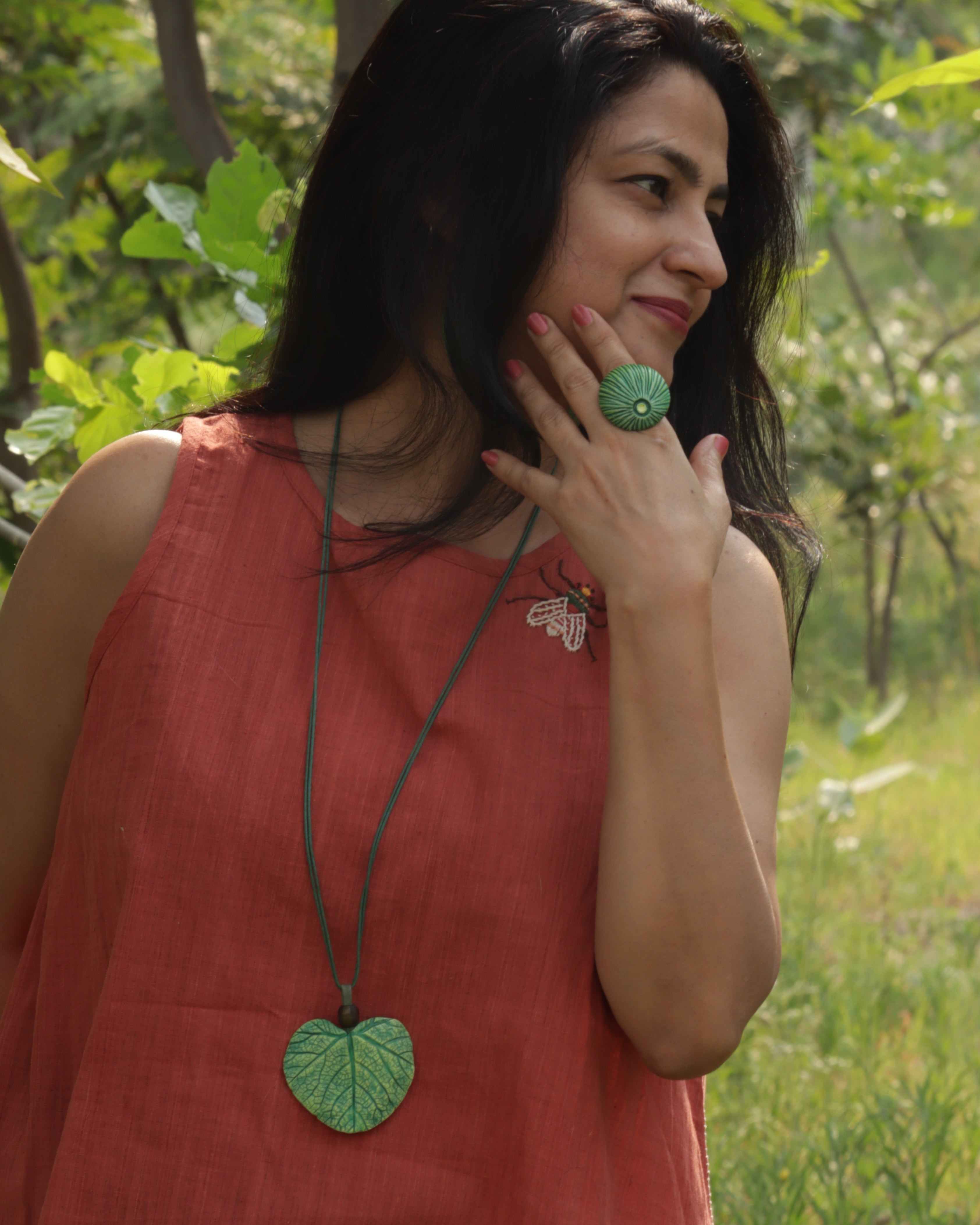 Woman in a red dress holding a green leaf-shaped object outdoors
